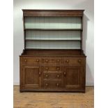 A small 18th century country oak dresser, the three height plate rack with projecting cornice and