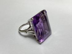 A single stone amethyst dress ring, the large emerald-cut stone claw-set in white metal on a white