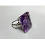 A single stone amethyst dress ring, the large emerald-cut stone claw-set in white metal on a white