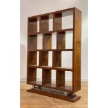 An Art Deco style walnut veneered open bookcase, with twelve open shelves, over silvered bun