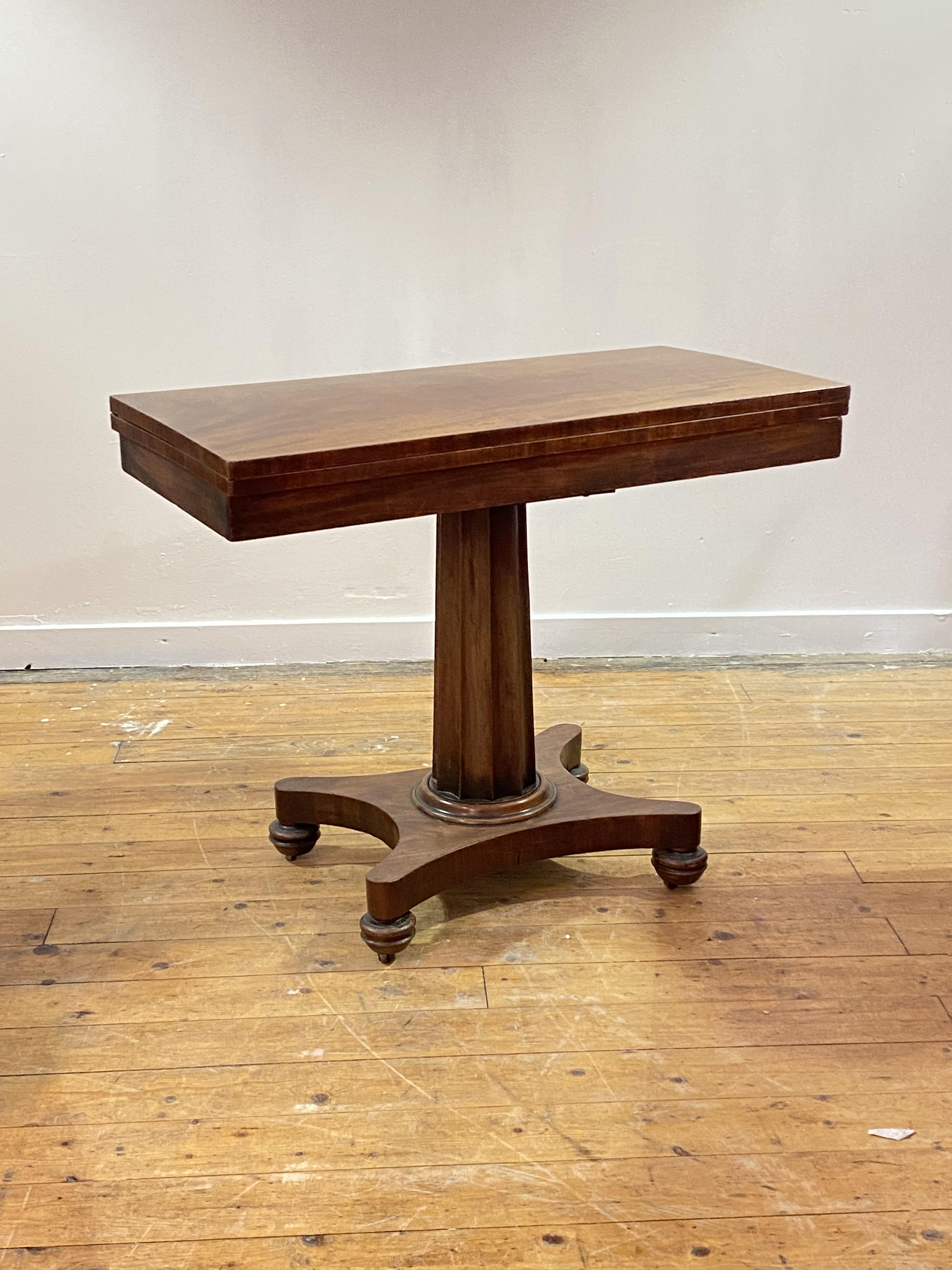 A mid 19th century mahogany supper table, the fold over revolving top over a fluted centre column,