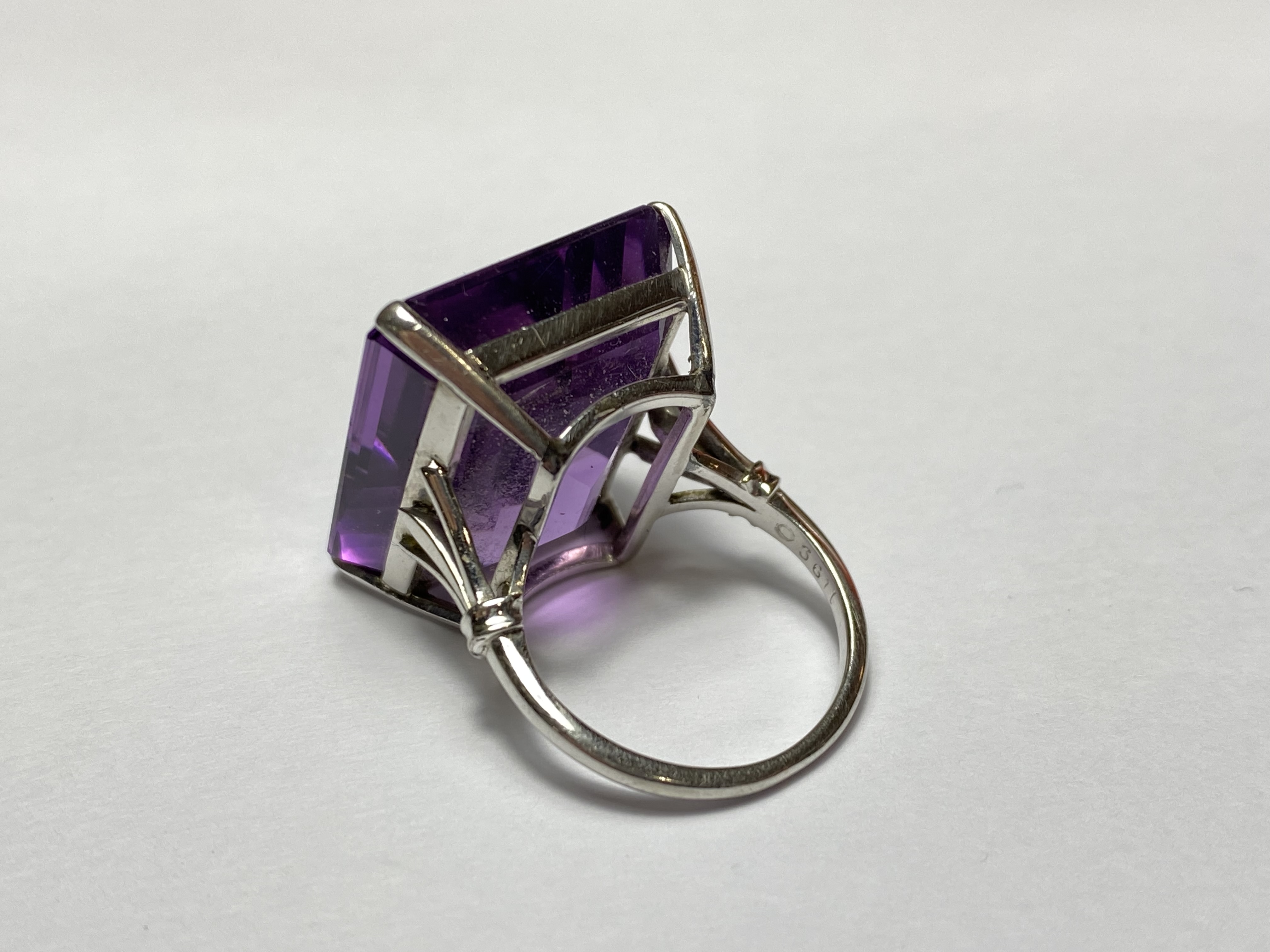 A single stone amethyst dress ring, the large emerald-cut stone claw-set in white metal on a white - Image 2 of 2