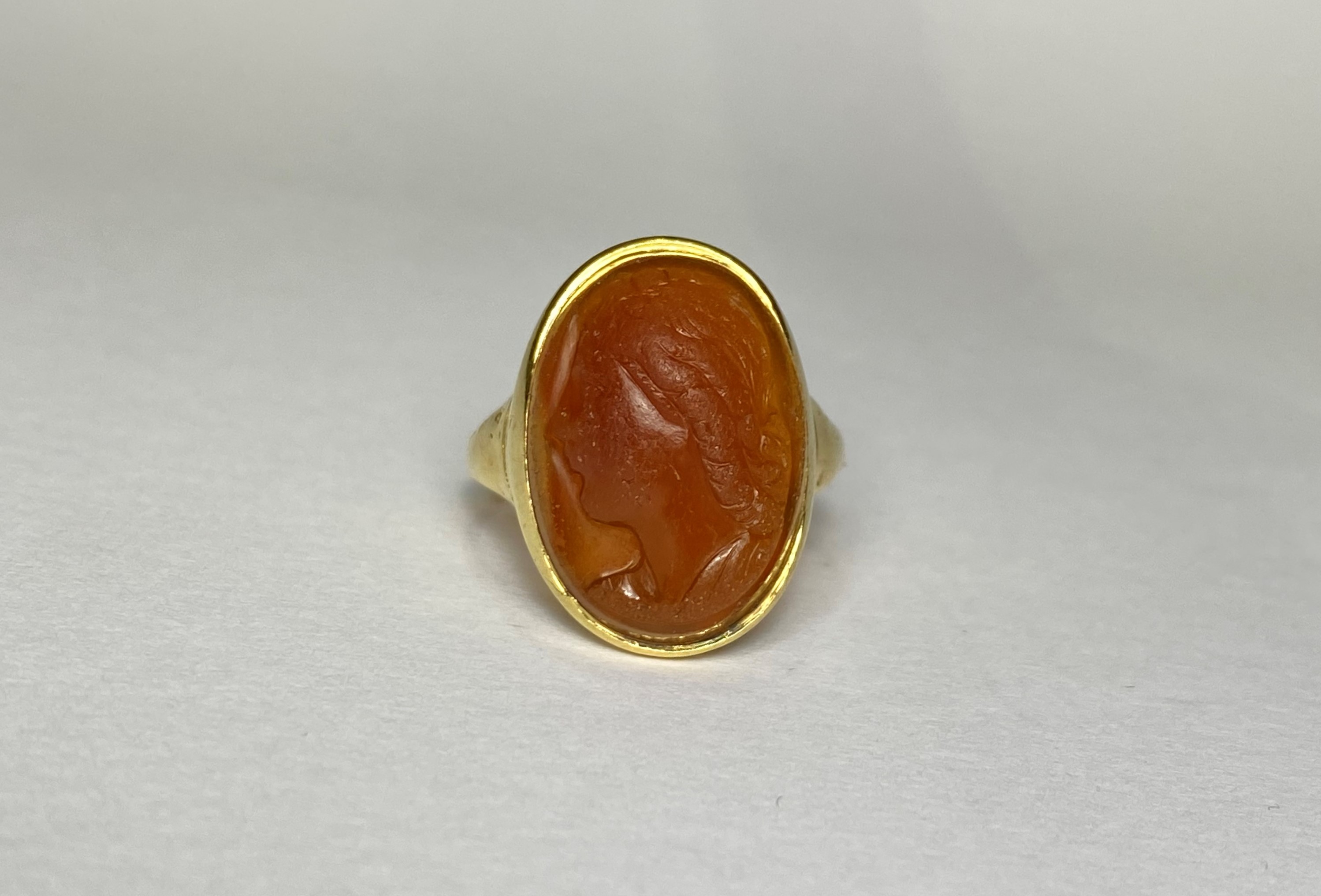 A carved hardstone intaglio ring, the oval agate with a profile bust of a young lady, on an (