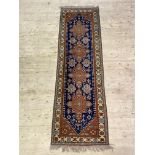 A Caucasian hand knotted runner, the deep blue field with pole medallion framed within an ivory
