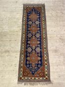 A Caucasian hand knotted runner, the deep blue field with pole medallion framed within an ivory