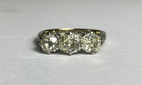 A three-stone diamond ring, the graduated round brilliant-cut stones claw-set on a platinum band.
