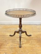 A George III mahogany tilt top tripod table, the circular top with turned spindle gallery over