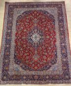 An Iranian hand-knotted carpet from the Kashan Region, the red field with blue and ivory medallion