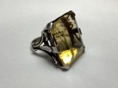 A striking single stone citrine dress ring, the large emerald-cut stone claw set on scroll and