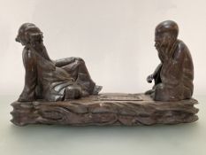 A Chinese wooden carving of two seated figures playing "Go", unsigned. Height 23cm, length 43cm