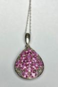 A pink sapphire pendant, the oval-cut sapphires claw set in a tear-shaped white metal mount, on a