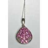 A pink sapphire pendant, the oval-cut sapphires claw set in a tear-shaped white metal mount, on a