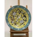 A Chinese yellow ground porcelain charger, painted with paired dragons amidst flowers, within a