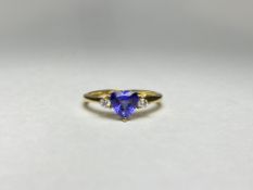 A tanzanite and diamond three-stone ring, the central trillion-cut tanzanite flanked by a pair of