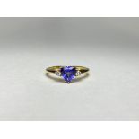 A tanzanite and diamond three-stone ring, the central trillion-cut tanzanite flanked by a pair of