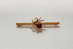 A 9ct gold bug brooch, the body of the insect millegrain-set with a reddish-brown stone, on a