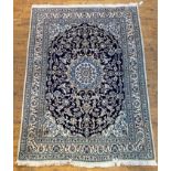 A Persian Nain hand knotted rug, the deep blue field with ivory medallion and arabesques, within a