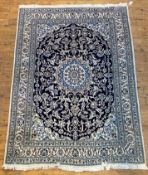 A Persian Nain hand knotted rug, the deep blue field with ivory medallion and arabesques, within a