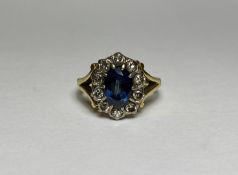 A sapphire and diamond cluster ring, the oval-cut sapphire within a band of ten claw-set old-cut