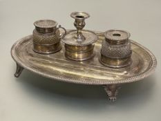 An early 19th century silver desk standish, the oval stand with gadrooned edge and raised on