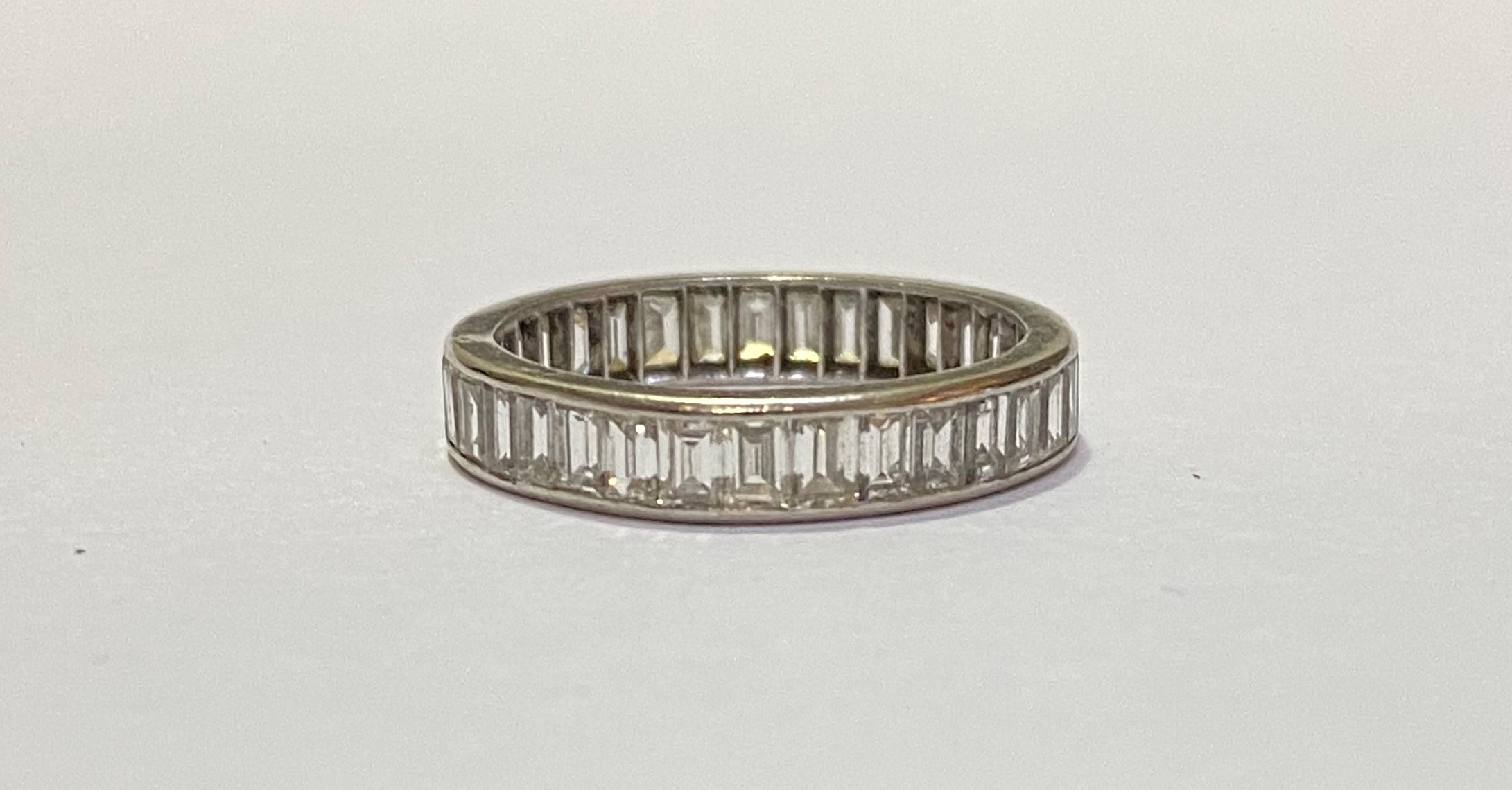 A diamond full hoop eternity ring, of channel-set baguette diamonds, in unmarked white metal. Ring