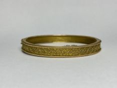 A Victorian 9ct gold hinged bangle, one half applied with wirework decoration, bearing