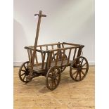 A rustic varnished pine dog cart, with spoked and coopered wheels and articulated steering, H71cm,