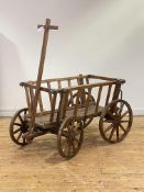 A rustic varnished pine dog cart, with spoked and coopered wheels and articulated steering, H71cm,