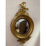 A carved gilt wood and gesso framed convex wall mirror, early 19th century, the top with stylized