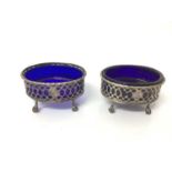 Pair of Georgian silver salt cellars of oval form with blue glass liners, on claw and ball feet (mar