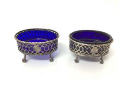 Pair of Georgian silver salt cellars of oval form with blue glass liners, on claw and ball feet (mar