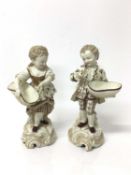 Pair of continental porcelain figures of a boy and girl, shown holding baskets, on scrollwork bases,