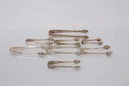 Seven pairs of Georgian and later silver sugar tongs, together with a pair of silver plated sugar to