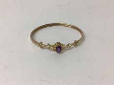 9ct gold and amethyst bangle with an oval mixed cut amethyst and gold scroll shoulders.