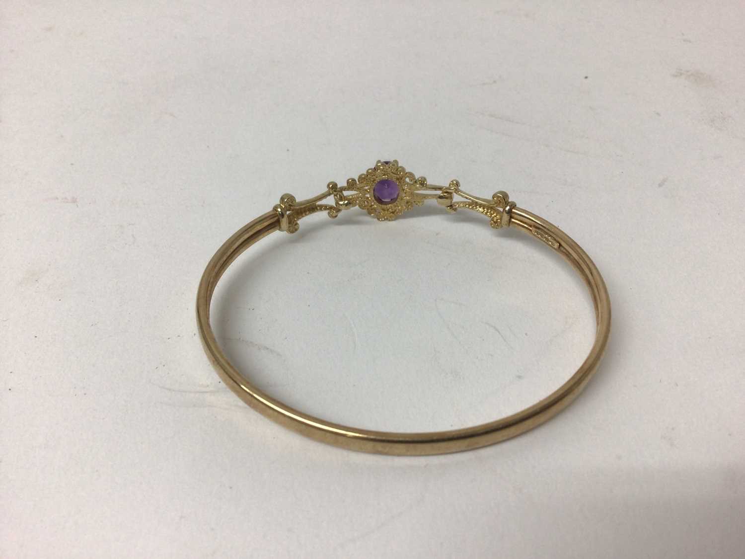 9ct gold and amethyst bangle with an oval mixed cut amethyst and gold scroll shoulders. - Image 2 of 2
