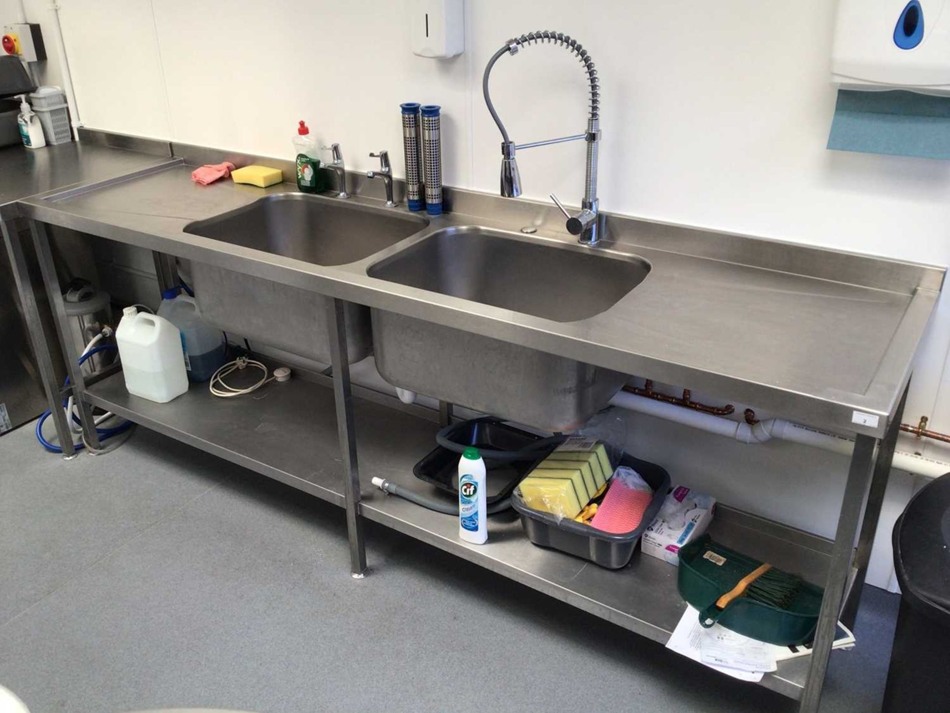 A stainless steel double bowl sink unit with pre-rinse flexi-hose tap and pair of taps, plus shelf