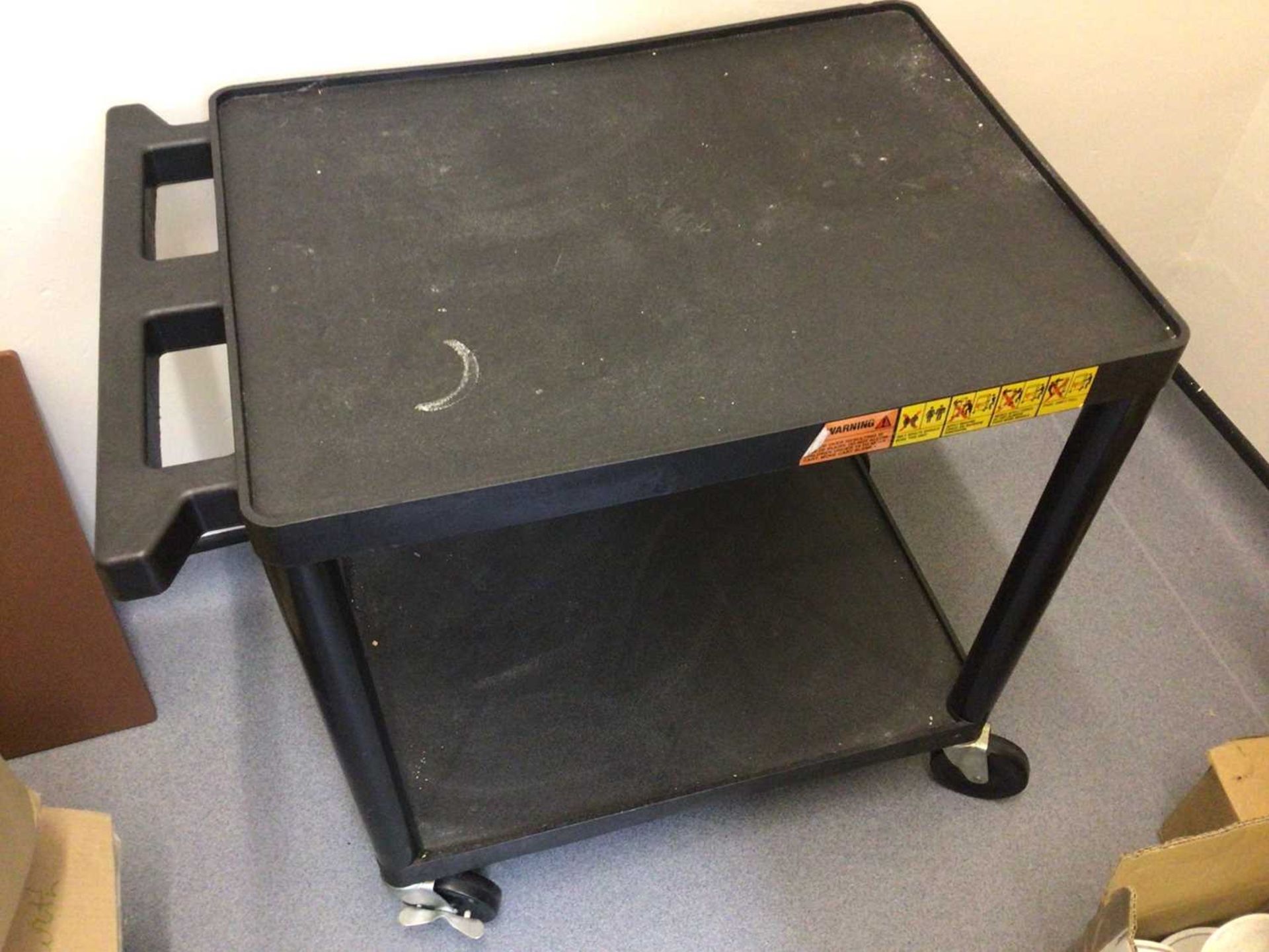 A black plastic two tier tea trolley, on castors, 610 mm x 460 mm