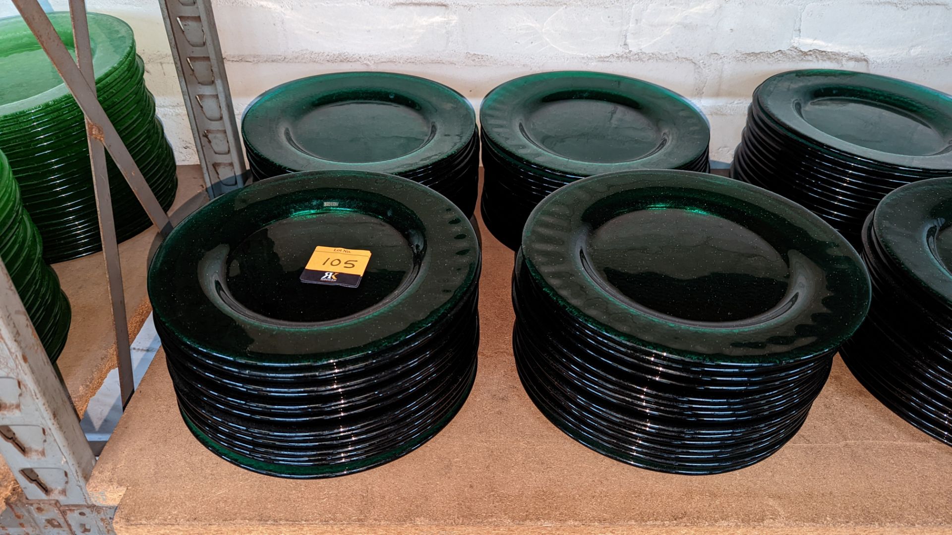 60 off dark green glass plates each measuring approximately 27cm diameter