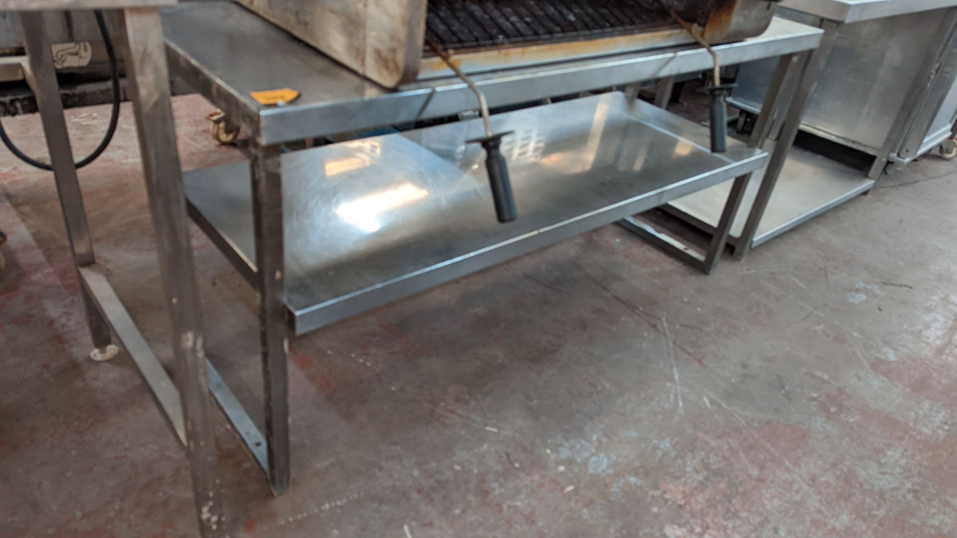 Stainless steel twin tier shelving system which appears to be designed for mounting on top of tables