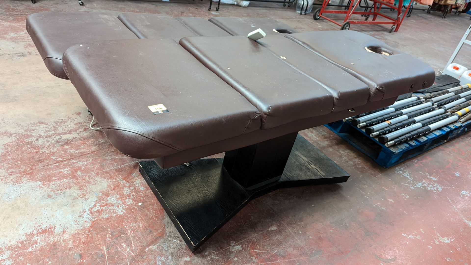 Beauty treatment bed in brown leather/leatherette on black wooden base with electric controller