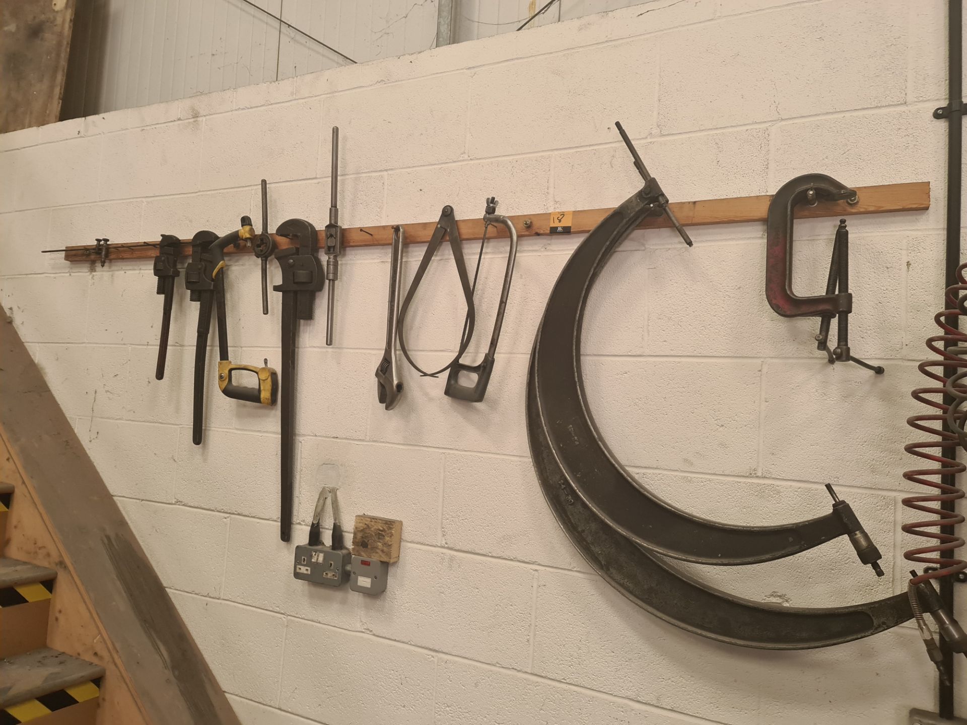 The contents of a wall mounted rack of tools, measuring equipment & more