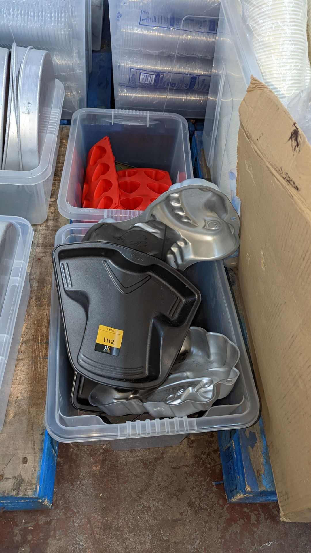 Contents of a crate of large novelty cake moulds in a style of sports shirts, unicorn, heart, dinosa