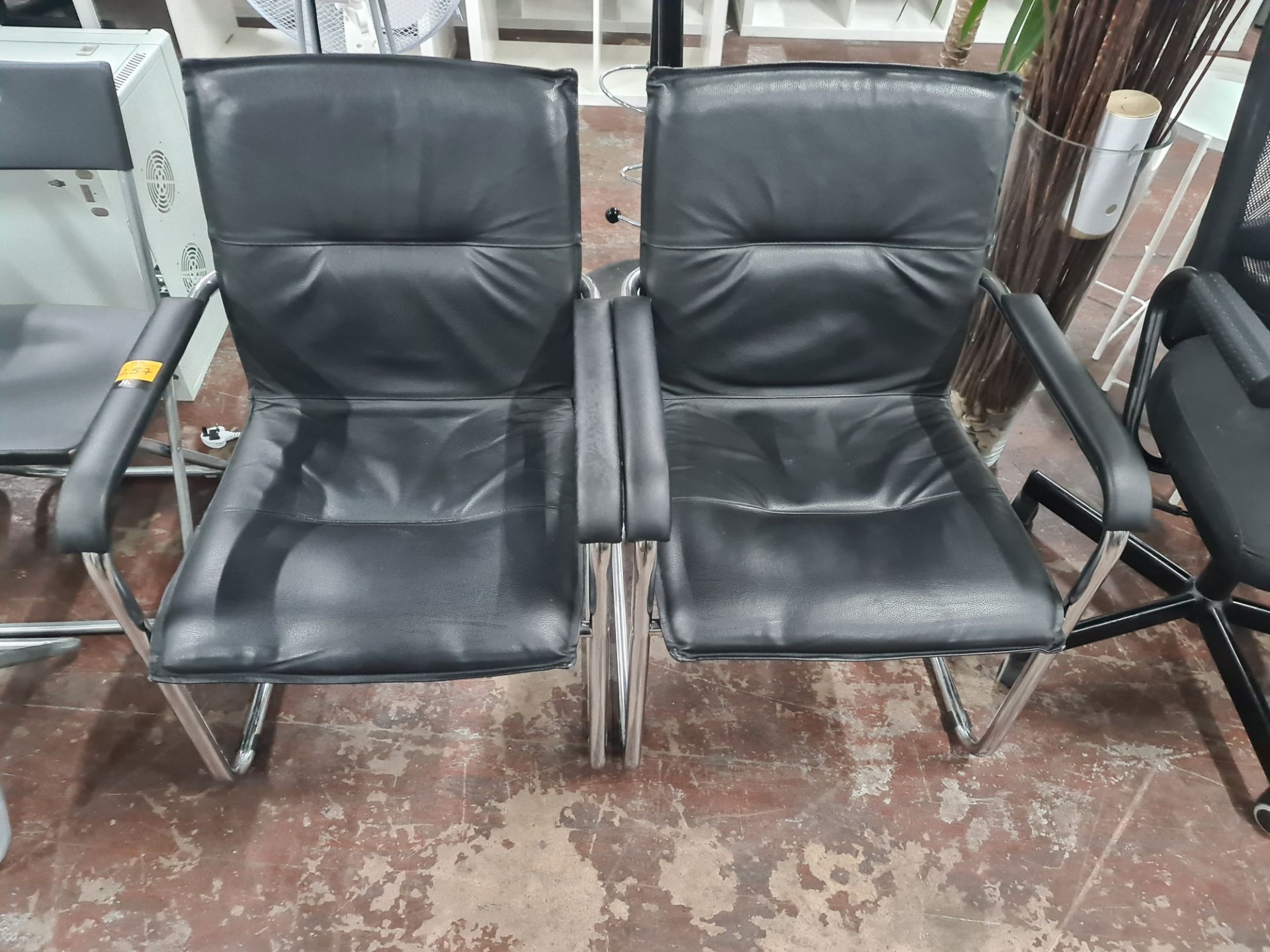 Pair of matching black leather/leather look upholstered chairs on chrome cantilever bases
