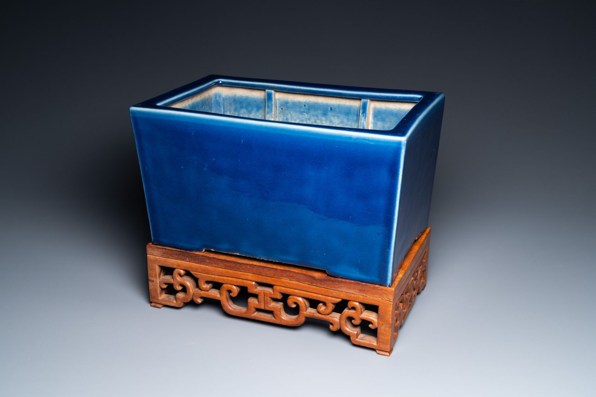 A Chinese rectangular blue-glazed jardiniere on wooden stand, 19th C.
