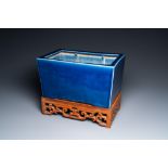 A Chinese rectangular blue-glazed jardiniere on wooden stand, 19th C.