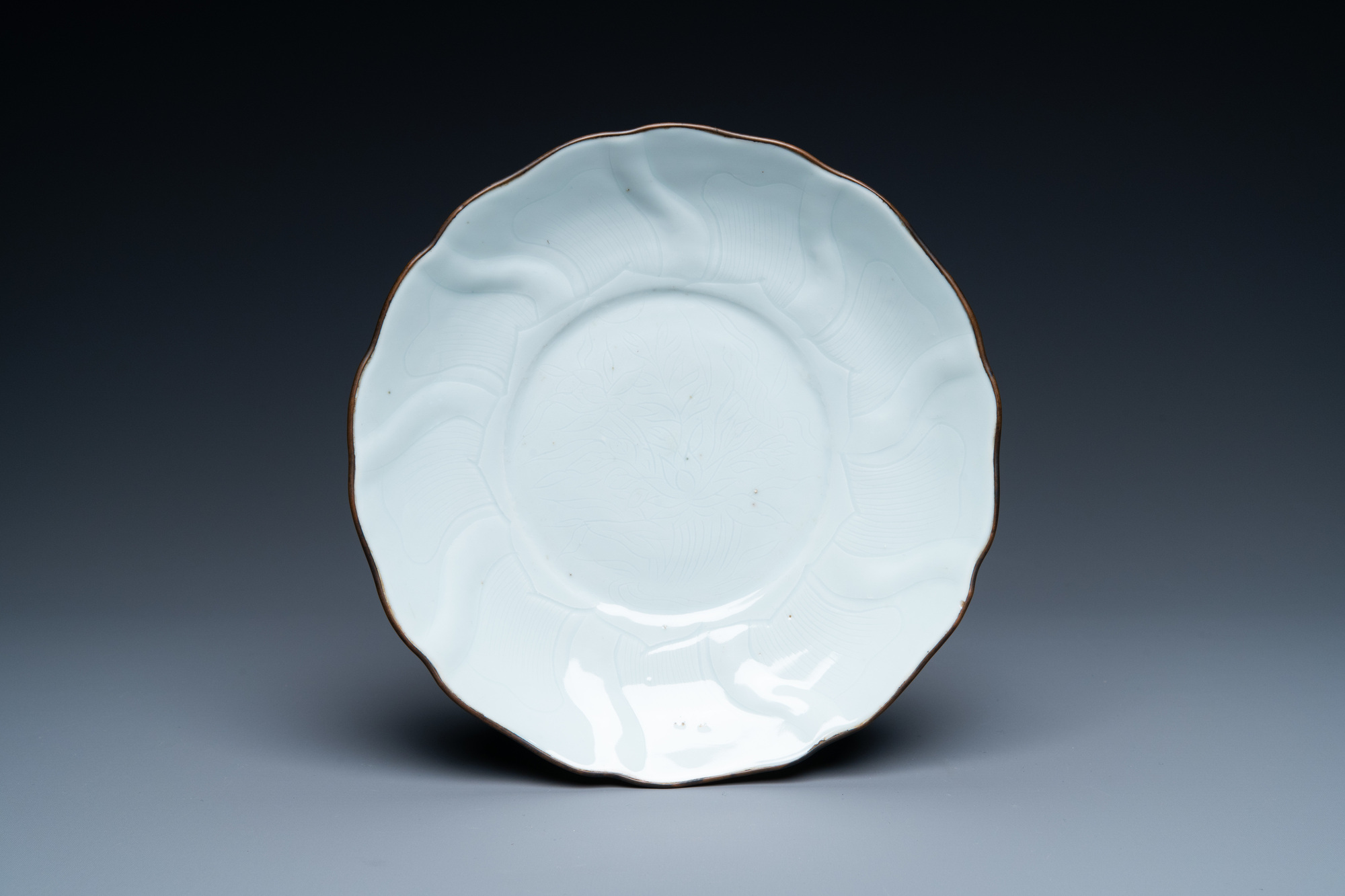 A Chinese molded white-glazed plate with incised lotus design, Xuande mark and of the period