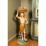 A polychrome terracotta 'Egyptomania' sculpture of an Egyptian lady with a flower basket, illegibly