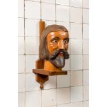 A large polychromed carved wooden head of a bearded man on a wooden console base, 19/20th C.