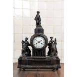 An ebonised mantel clock with romantic figures and topped with a putto, 19th C.