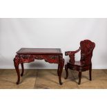 A finely carved Japanese red patinated wooden desk with armchair, 20th C.